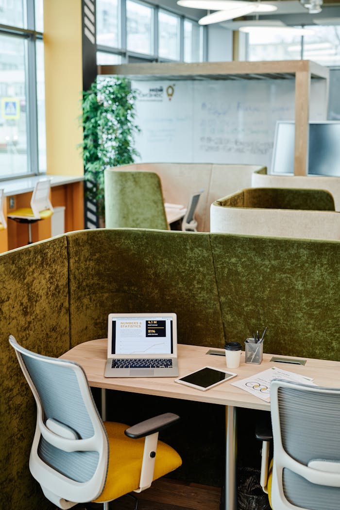 Cozy modern office workspace with a laptop, tablet, and green partitions for privacy.